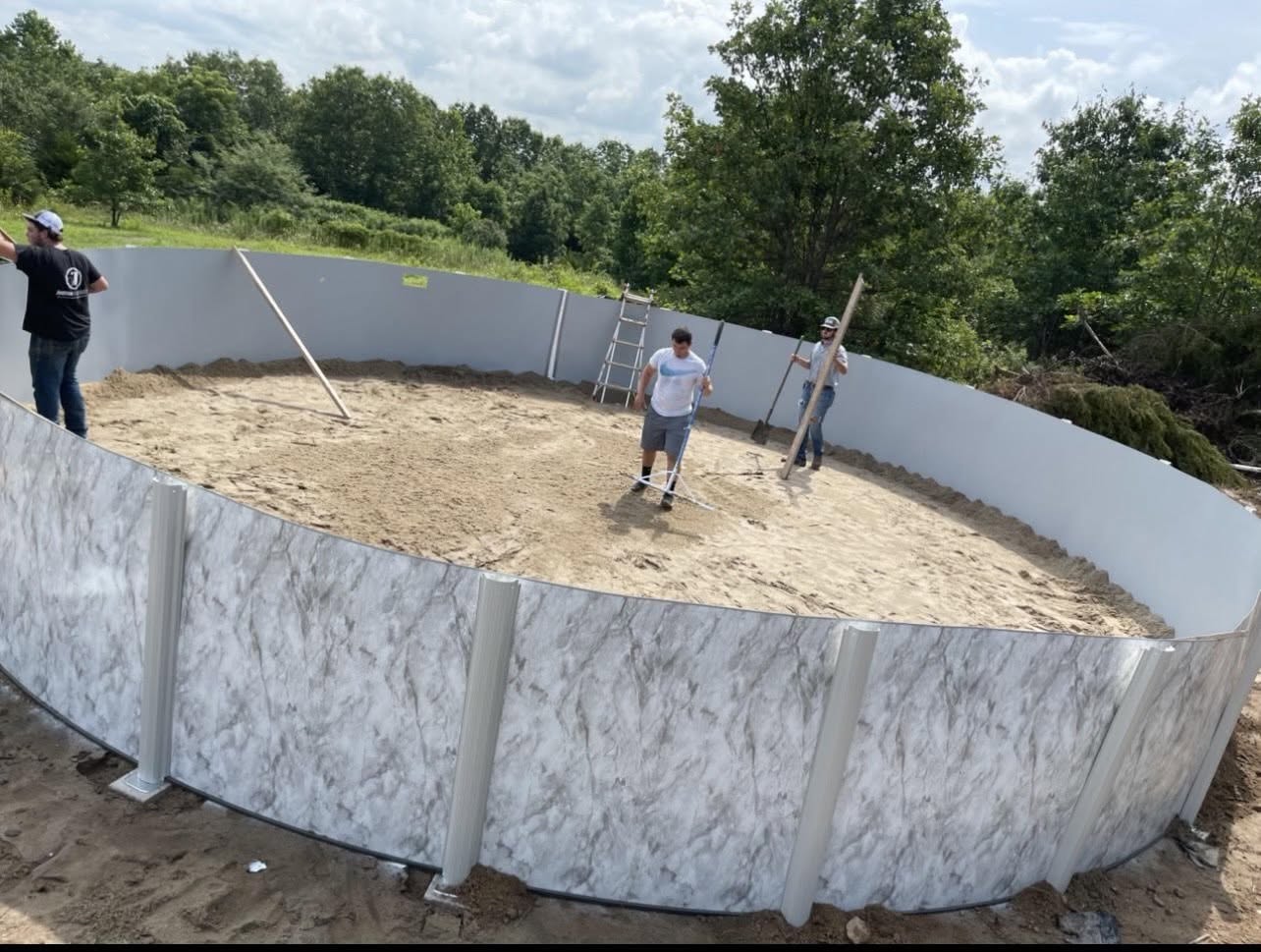 People working inside an above-ground pool shell during installation, from the business’s public photographs